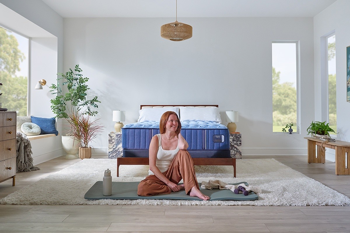 A woman sitting on a yoga mat in a styled bedroom