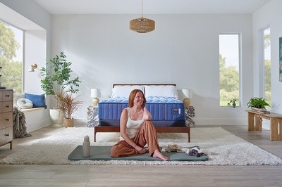 A woman sitting on a yoga mat in a styled bedroom