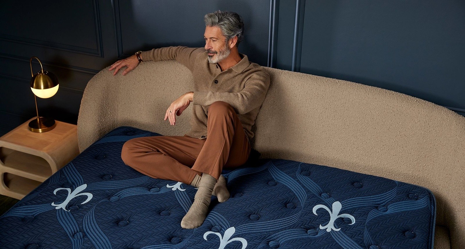 A man sitting on a medium hybrid legacy mattress