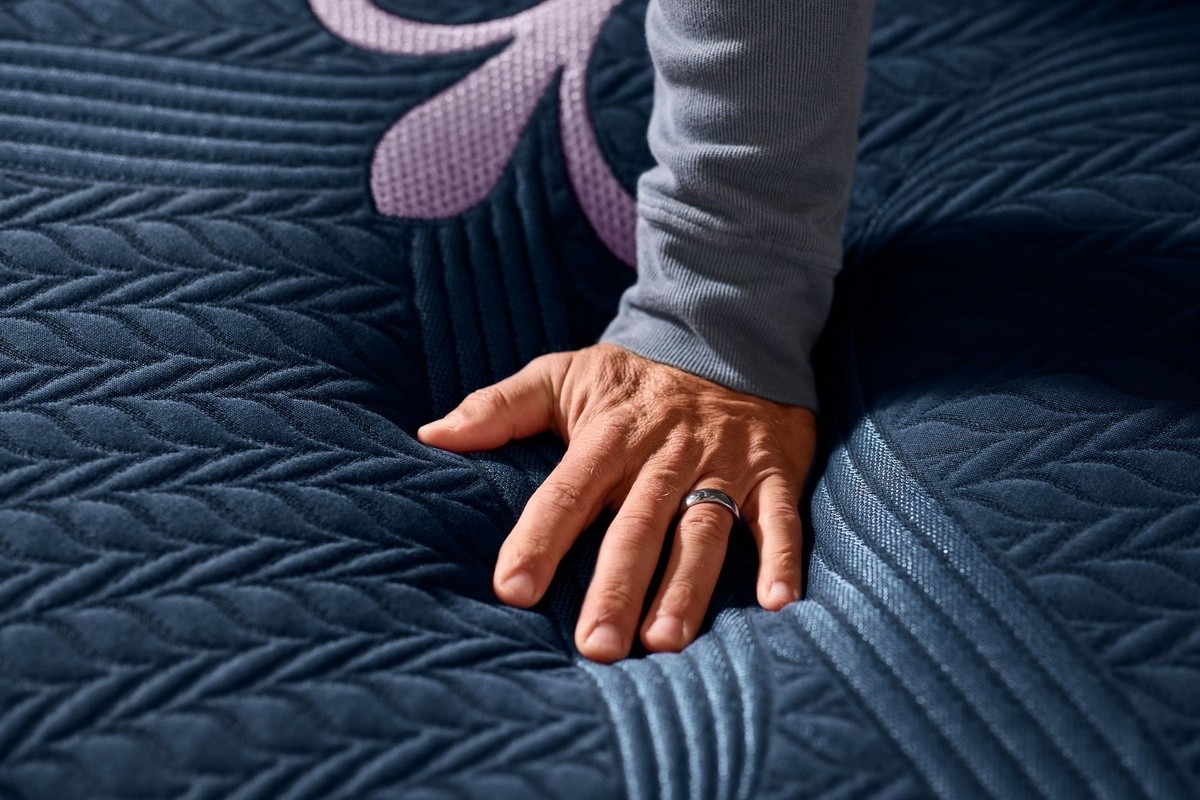 Hand pressing down into a legacy medium hybrid mattress