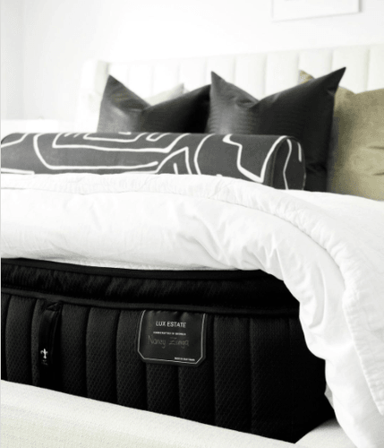 Stearns and Foster mattress dressed with a white comforter and grey patterned throw pillows.png
