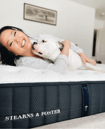 A woman and dog laying on a mattress