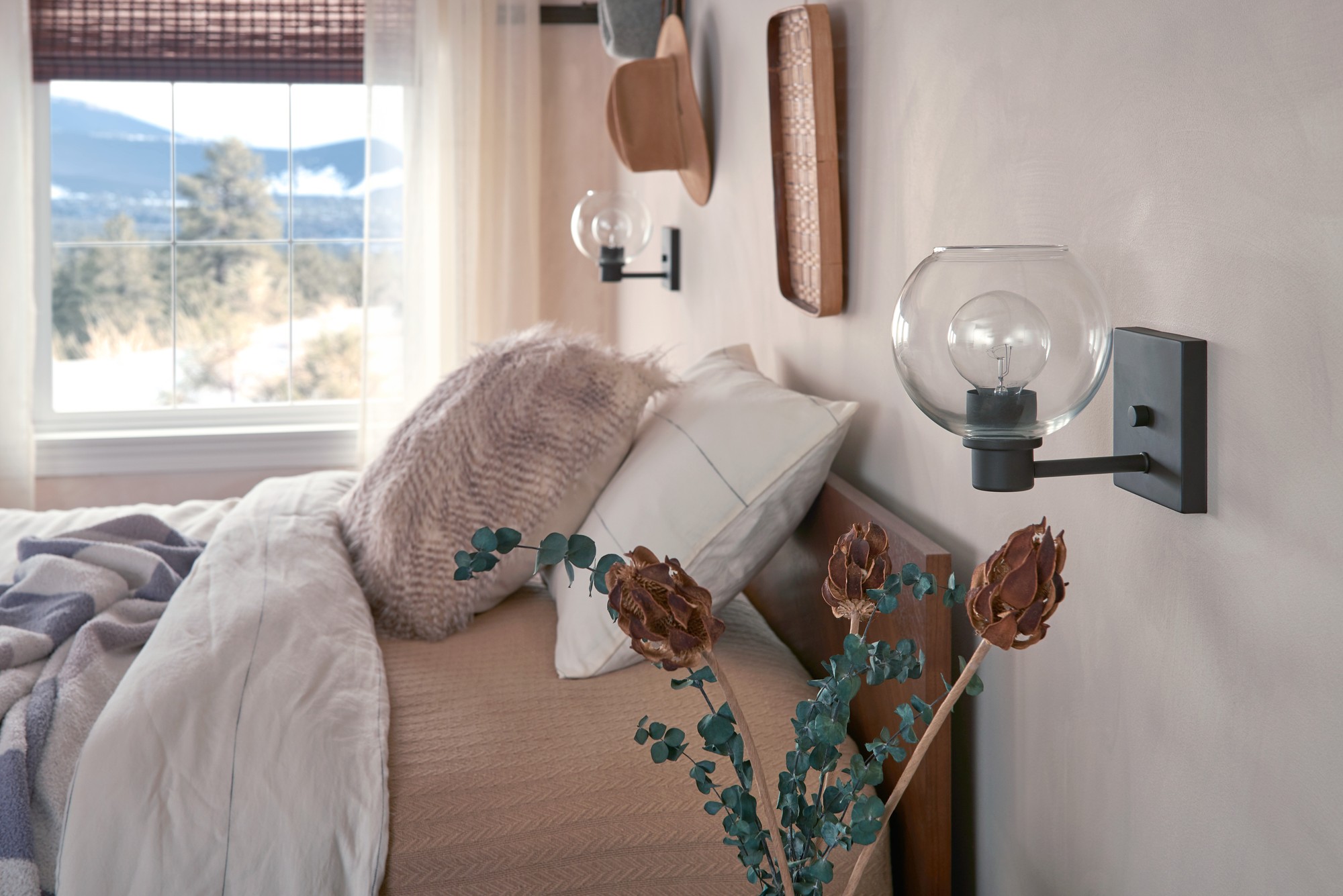 made bed with autumn accent colors and a vase with greenery and burnt orange flowers sitting on the night stand
